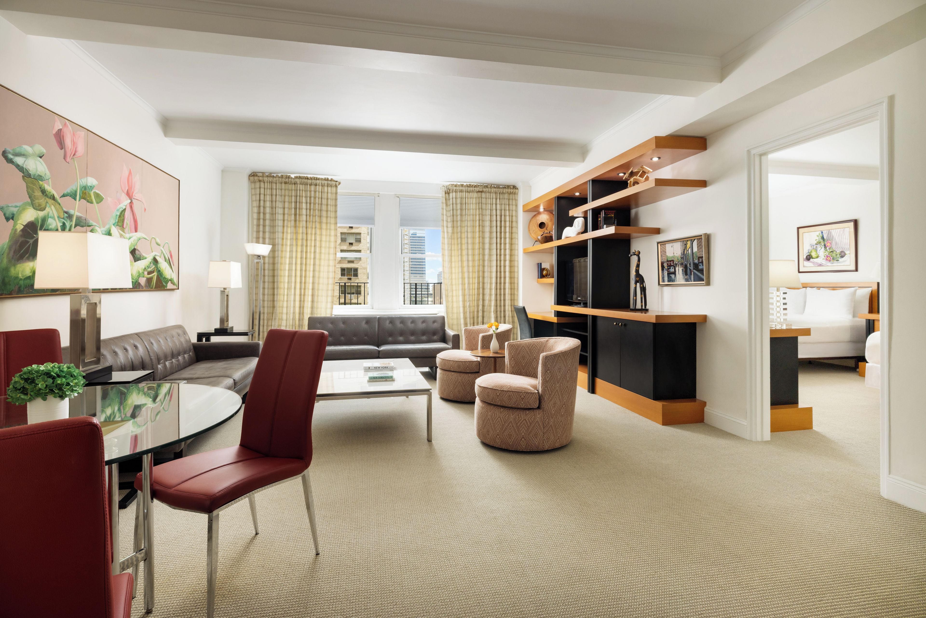 A modern hotel room with a living area, a dining space, and a bedroom.