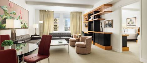 A modern hotel room with a living area, a dining space, and a bedroom.