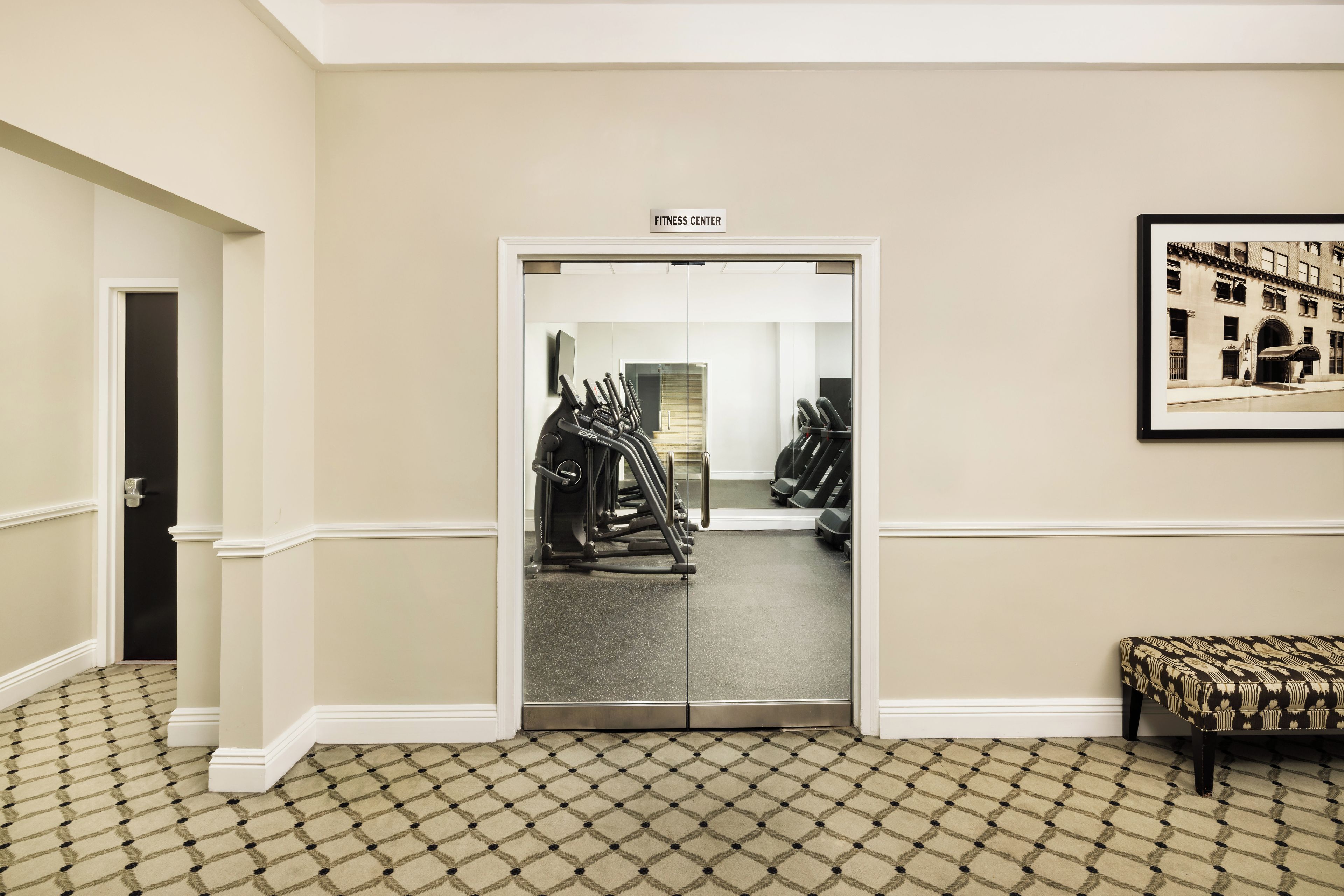 A fitness center with treadmills and exercise equipment, a door labeled 'FITNESS CENTER', and a patterned carpet.