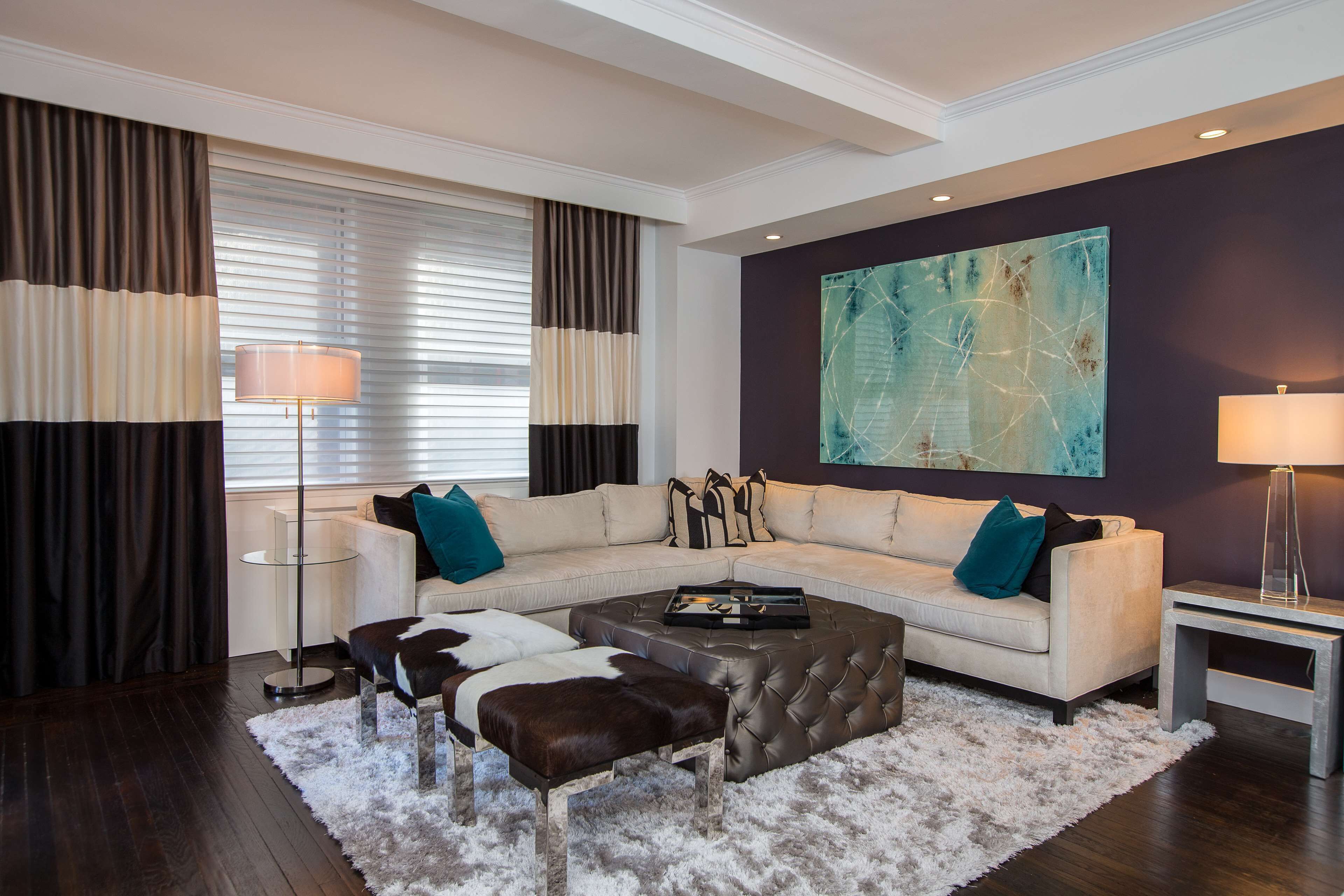 A modern living room with a sectional sofa, a coffee table, and a large abstract painting on the wall.