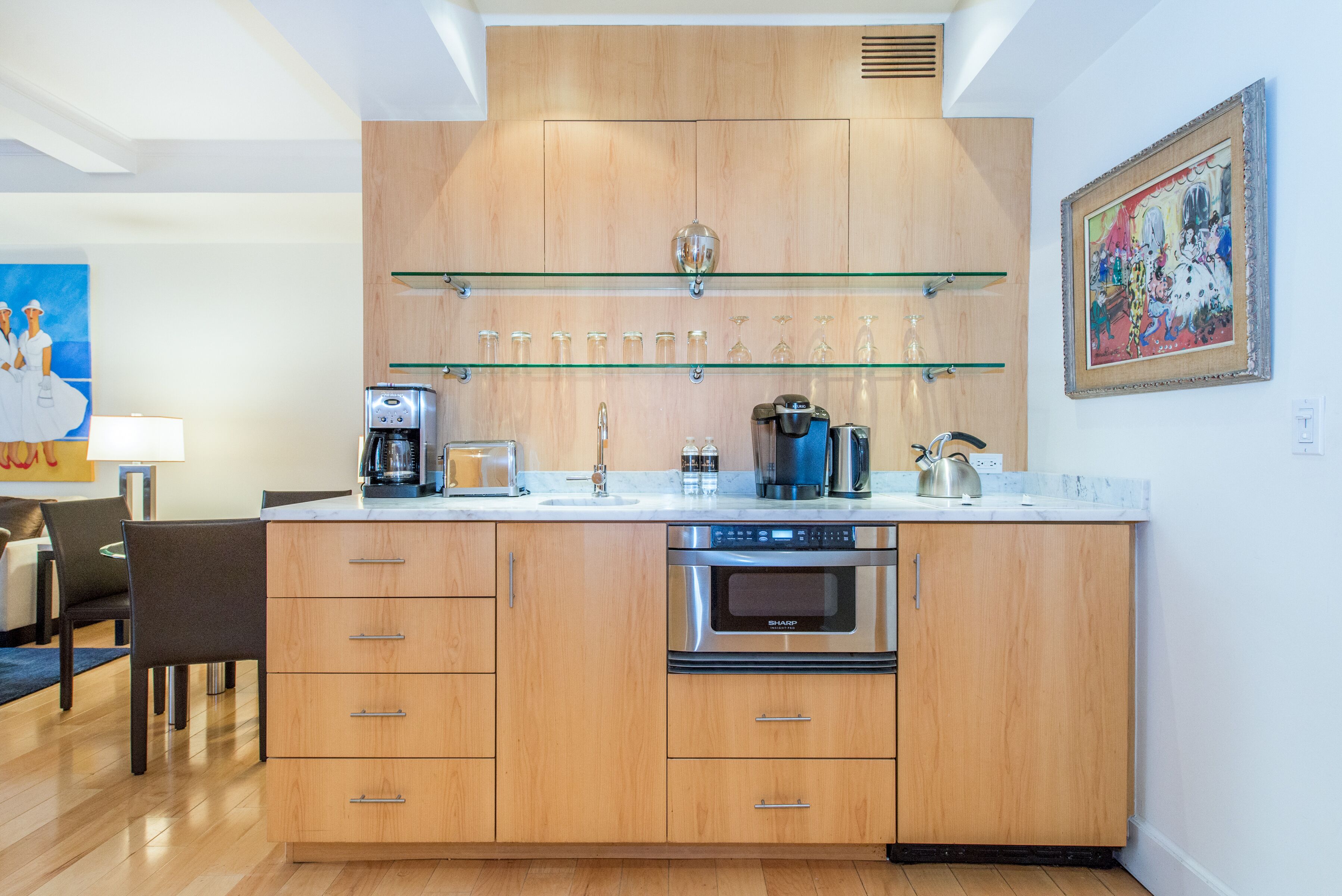 A modern kitchen with wooden cabinets, a built-in oven, and a glass shelf above the counter.