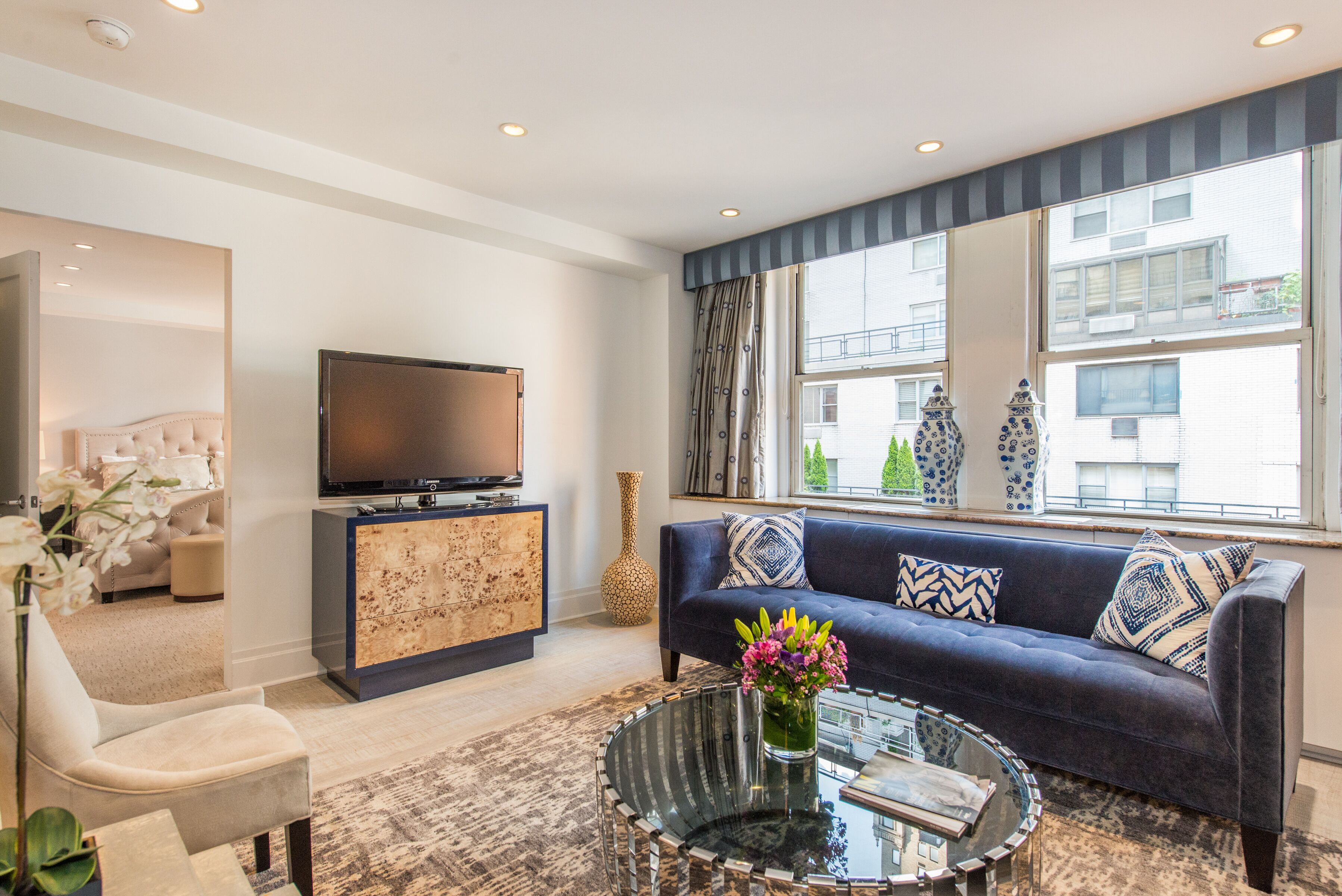 A modern living room with a sofa, a glass coffee table, a TV, and decorative vases.