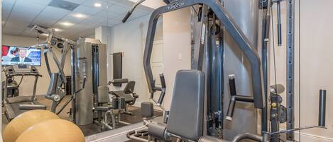 Un gimnasio con diversos equipos de ejercicio, incluyendo una cinta de correr, máquinas de pesas y pelotas de entrenamiento.