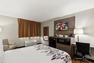 Habitación de hotel con cama, escritorio, silla, televisor y minibar.