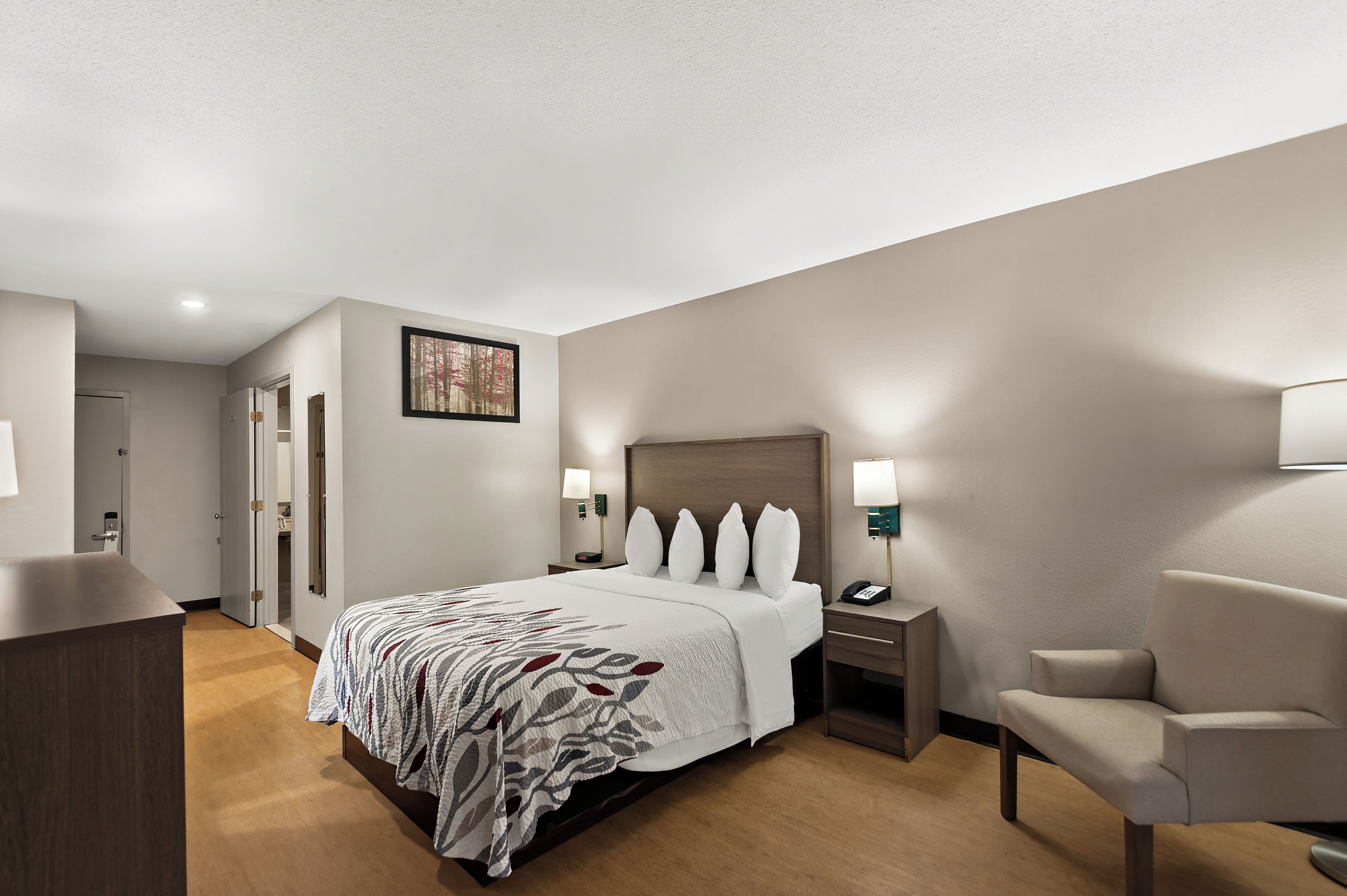 Una habitación de hotel con cama, mesitas de noche, una silla y un escritorio.
