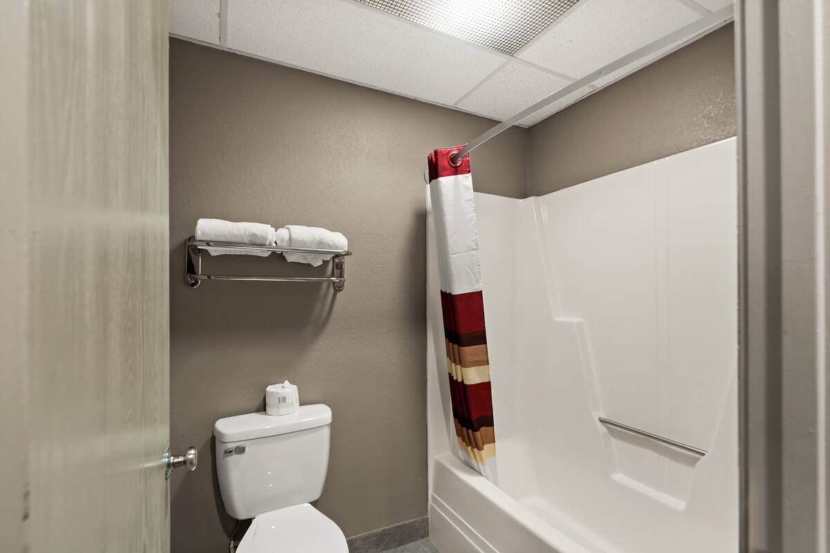 A bathroom with a toilet, a towel rack, and a shower with a striped curtain.
