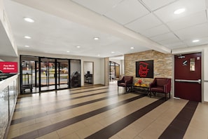 A hotel lobby with a reception desk, seating area, and a sign for the Red Roof Inn. - Red Roof Inn Martinsburg (Martinsburg)