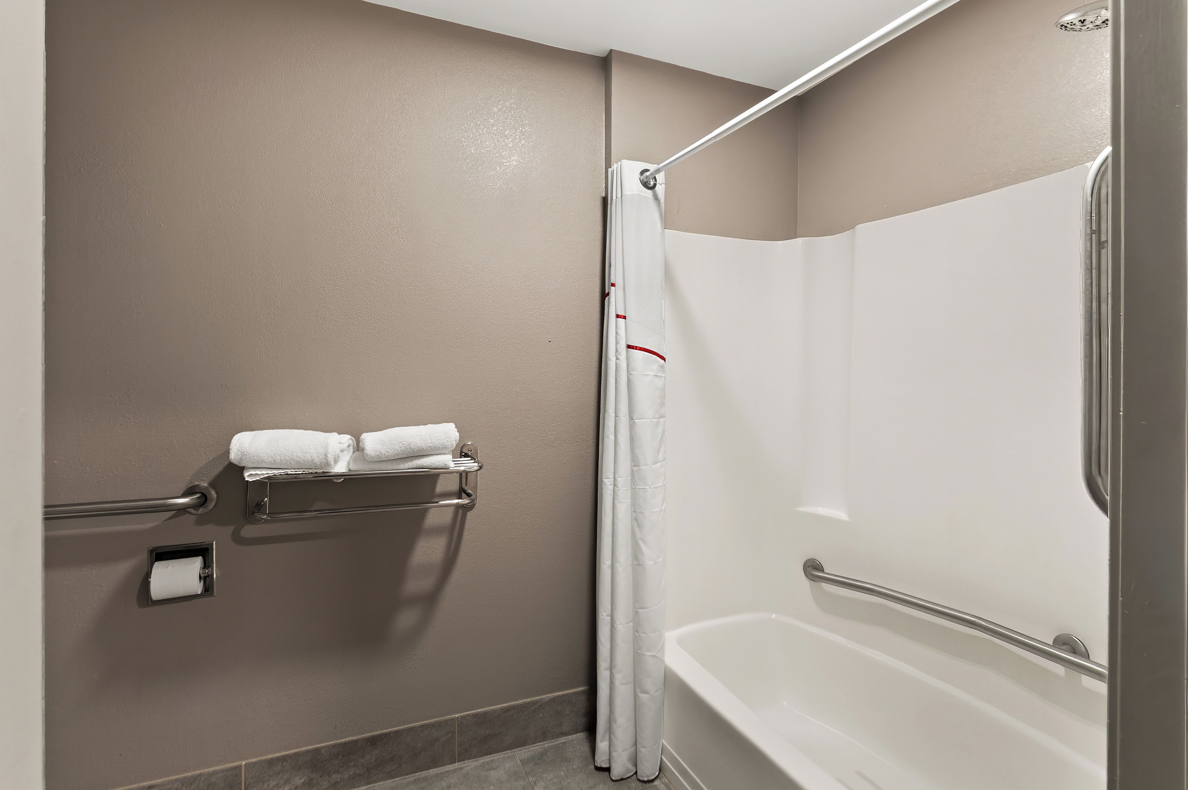 A bathroom with a bathtub, a shower curtain, and a towel rack with two towels.