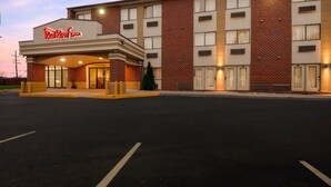 Un Red Roof Inn con fachada de ladrillo, varias ventanas y una entrada bien iluminada.