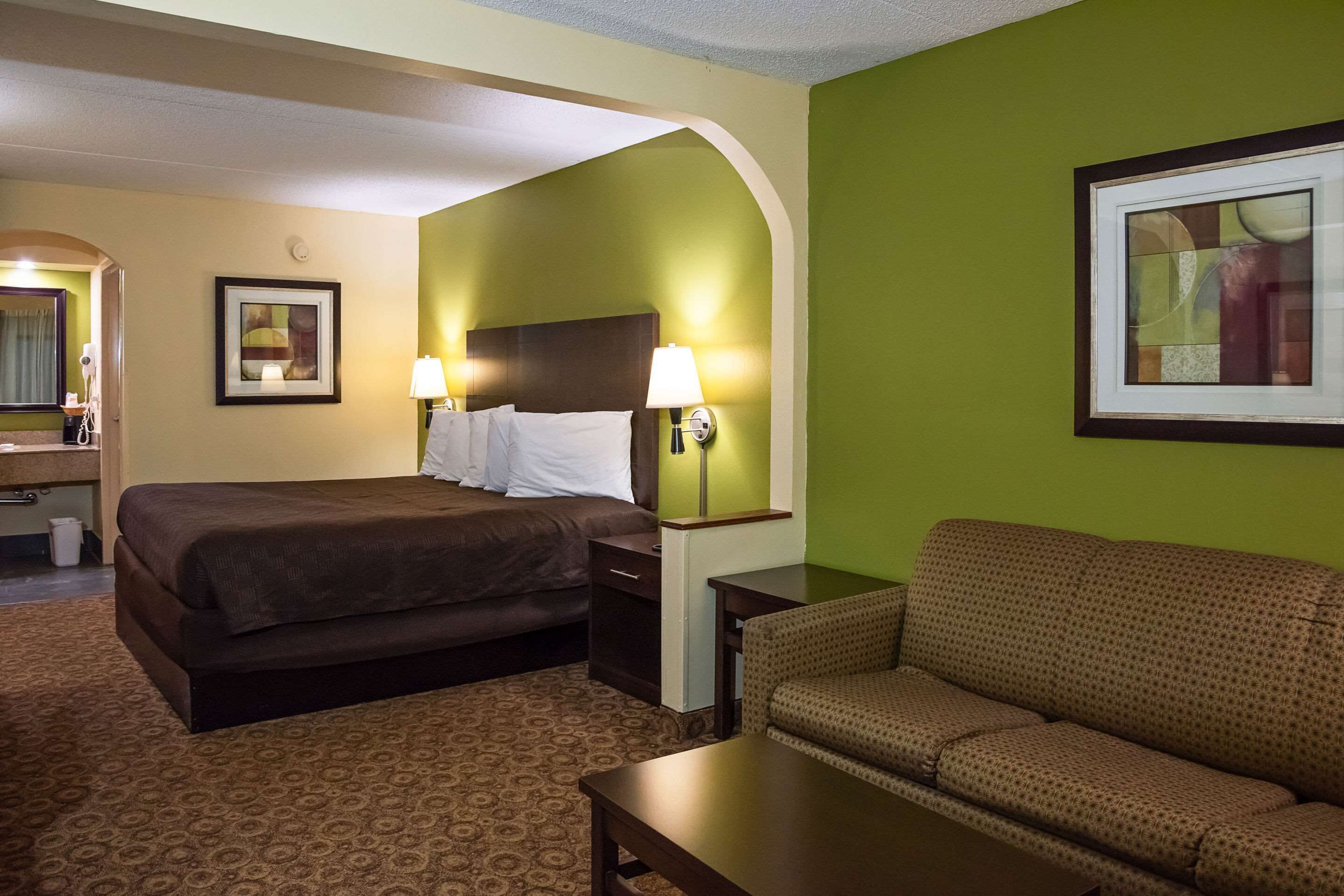 Una habitación de hotel con cama, sofá, escritorio y lámpara.