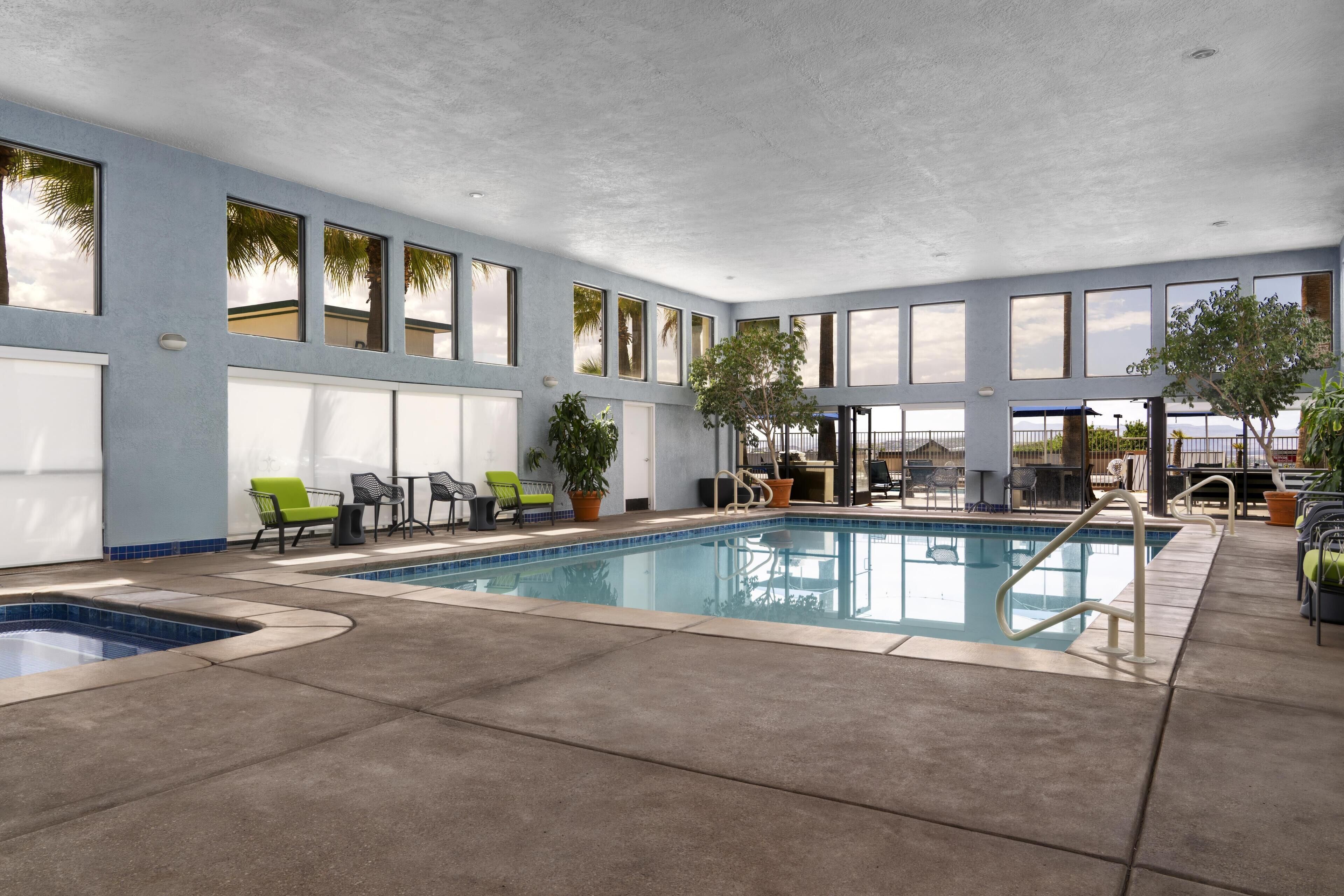 Una piscina techada, una piscina al aire libre, sombrillas