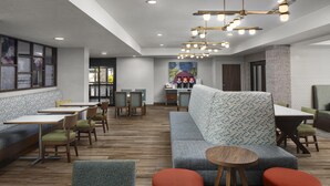 Un hall d’hôtel moderne doté d’un espace salon, d’un coin café et d’une grande fenêtre.