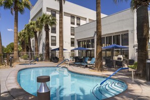 Une piscine au design incurvé, entourée de palmiers et de chaises longues.