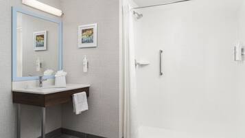 A modern bathroom with a shower, a sink with a mirror, and two framed pictures on the wall.