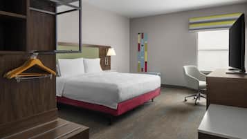 Een hotelkamer met een bed, een bureau, een stoel, een televisie en een kledingkast.
