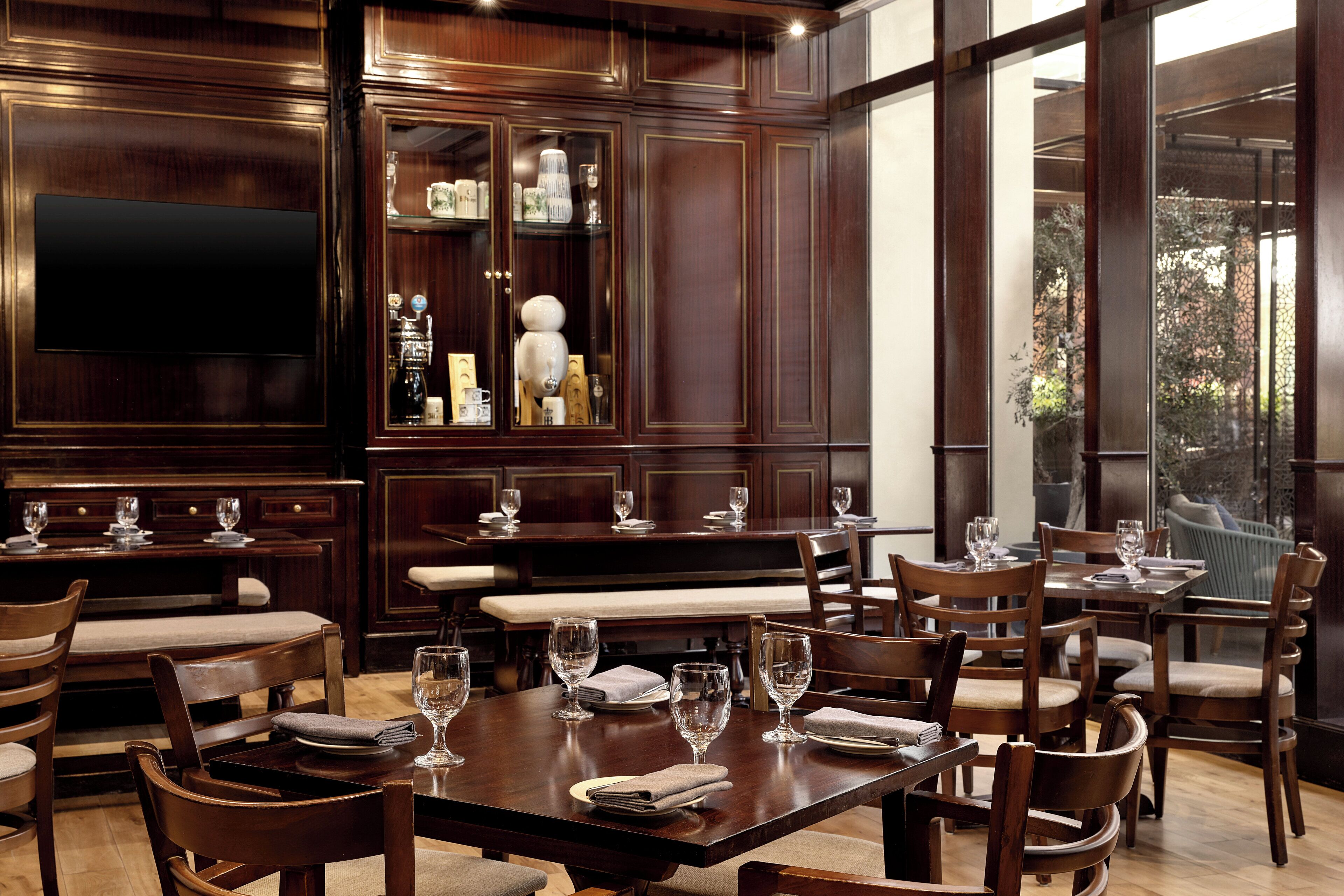 A restaurant with wooden furniture, glassware, and a large window.