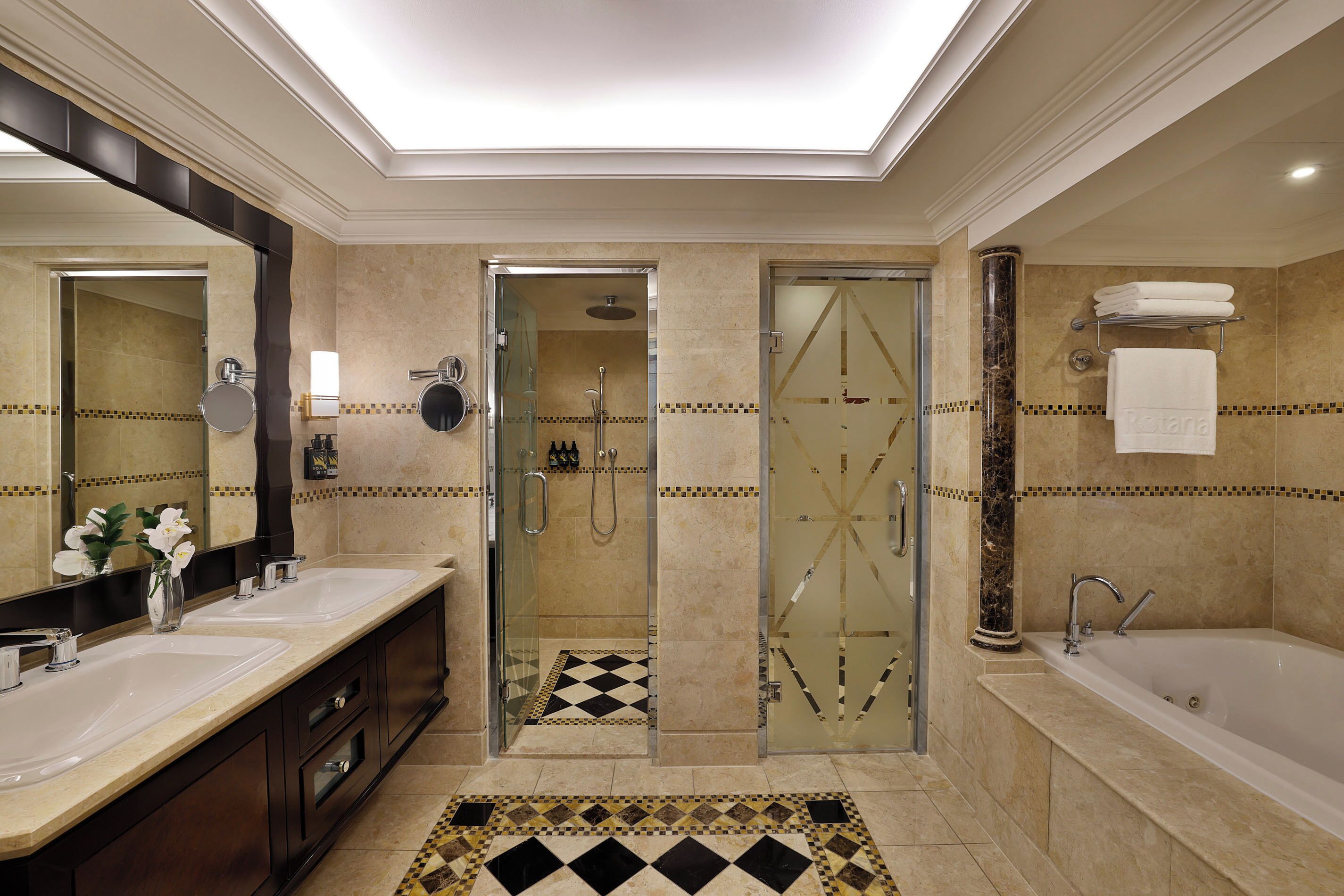 A modern bathroom with two sinks, a glass-enclosed shower, and a separate bathtub.