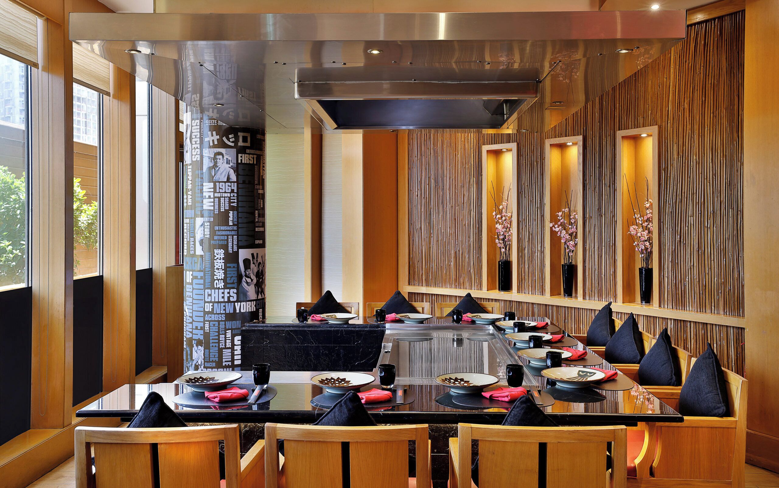 A restaurant with a long communal table, wooden chairs, and a modern interior design.