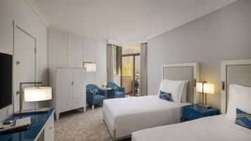 Une chambre d’hôtel avec deux lits, un bureau avec une lampe, une télévision et une chaise.
