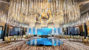 A grand hall with a central stage, ornate chandeliers, and a reflective floor. - Beach Rotana (Abu Dhabi)