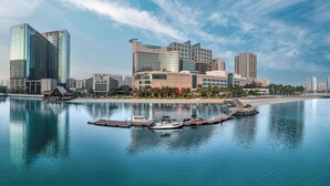 Un hôtel situé au bord de l’eau, doté d’une architecture moderne, d’un port de plaisance avec des bateaux et d’une plage.