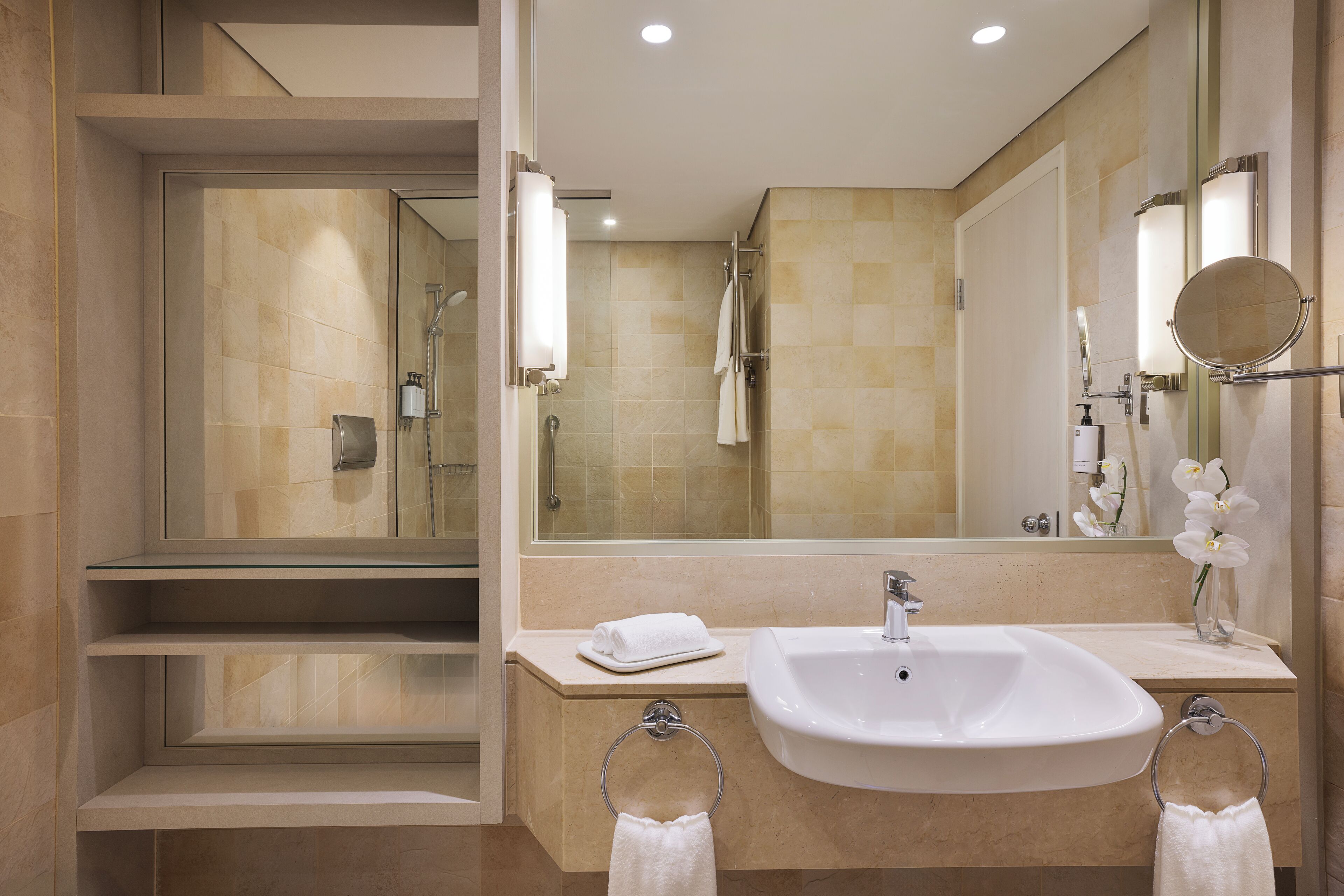 Un baño moderno con ducha de vidrio, lavamanos con espejo y un perchero para toallas.