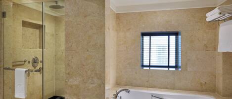 A modern bathroom with a glass-enclosed shower, a large bathtub, and a small window providing natural light.