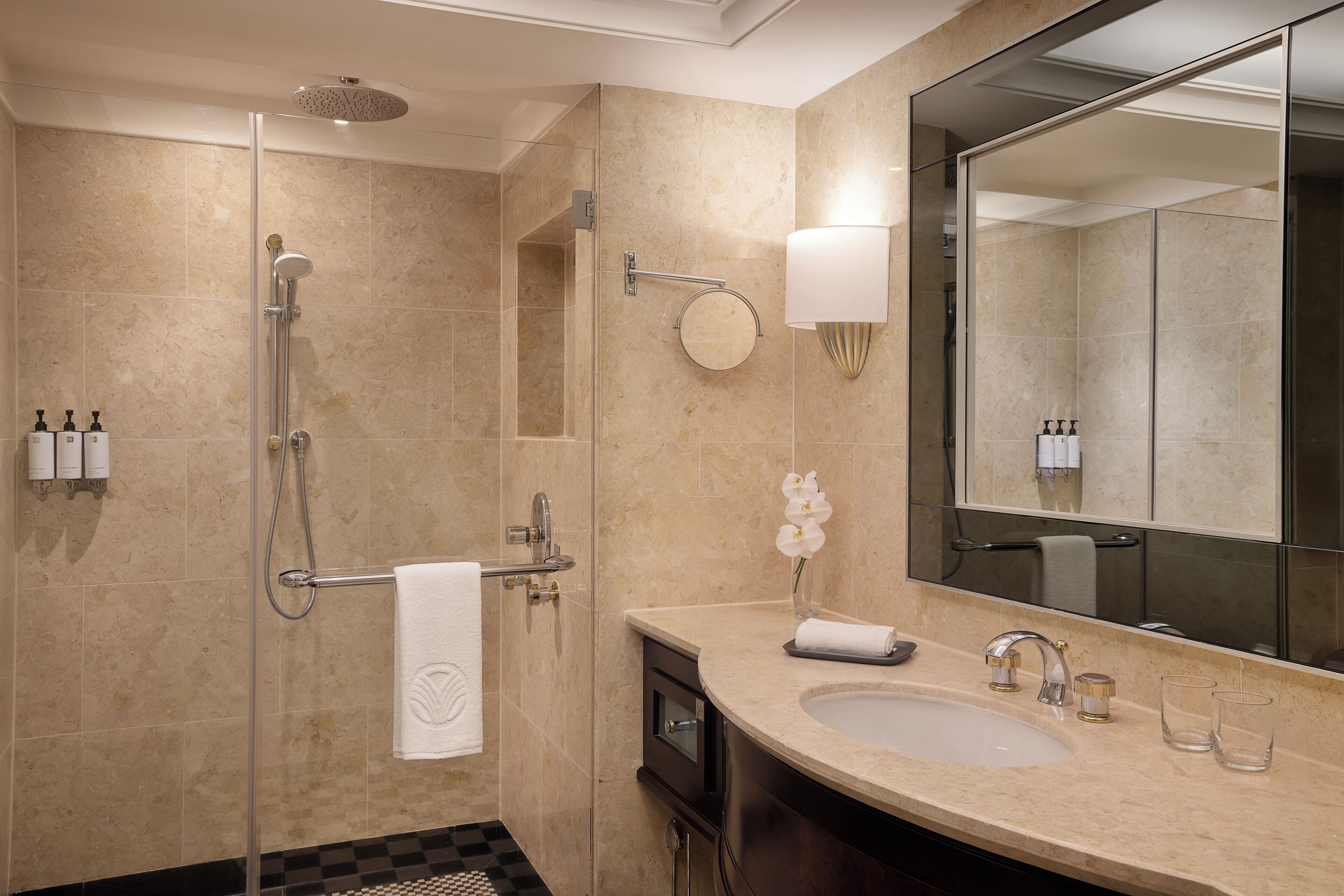 Un bany modern amb plat de dutxa envoltat de vidre, un mirall gran i un lavabo amb dues aixetes.