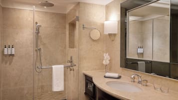 A modern bathroom with a glass-enclosed shower, a large mirror, and a sink with two faucets.