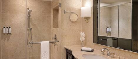 Un baño moderno con cabina de ducha de vidrio, un espejo grande y un lavabo de dos grifos.