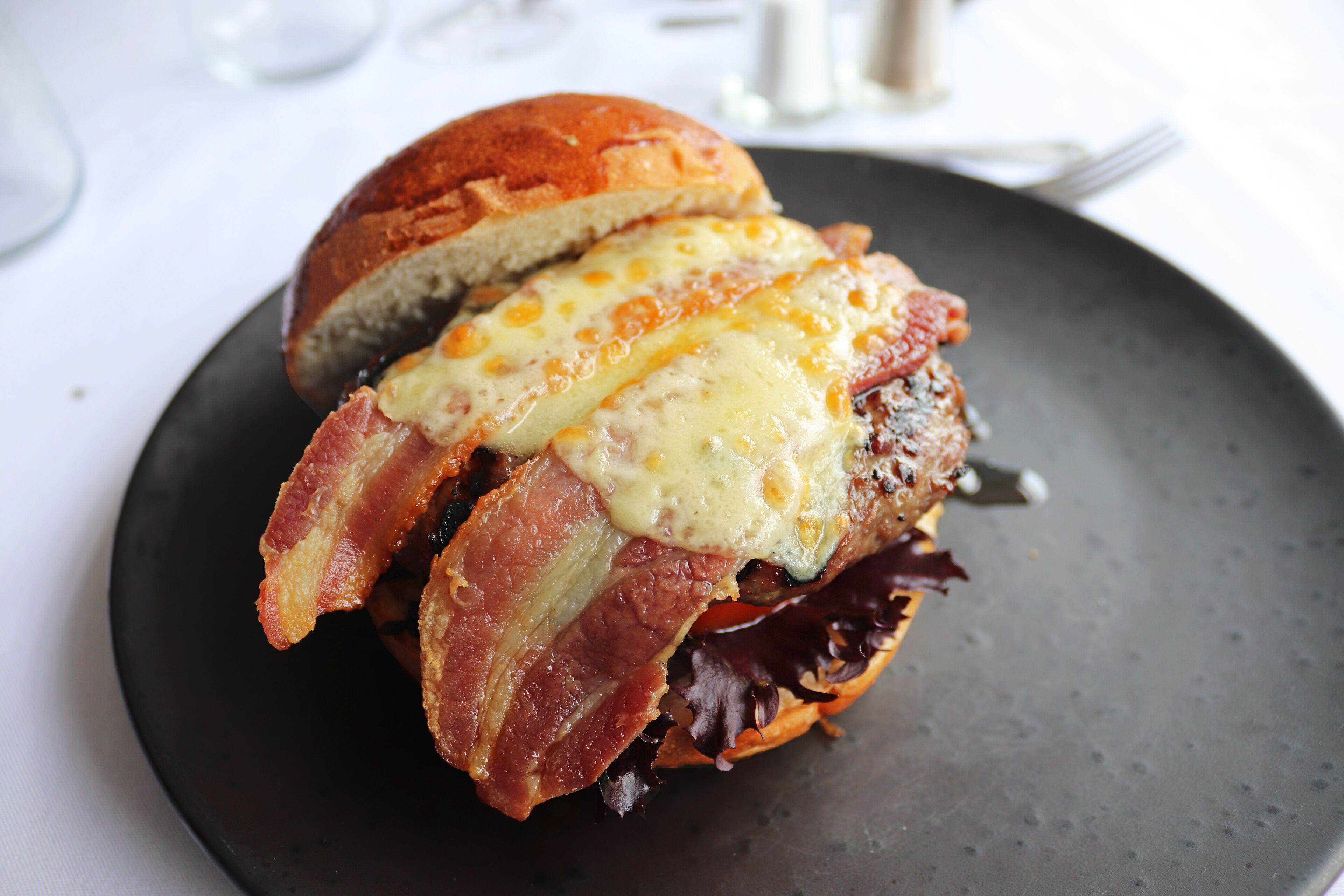 Un sándwich de tocino y queso sobre un plato oscuro.