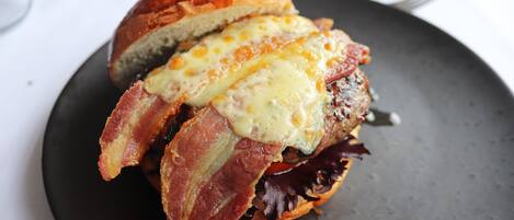 Un sándwich de tocino y queso sobre un plato oscuro.