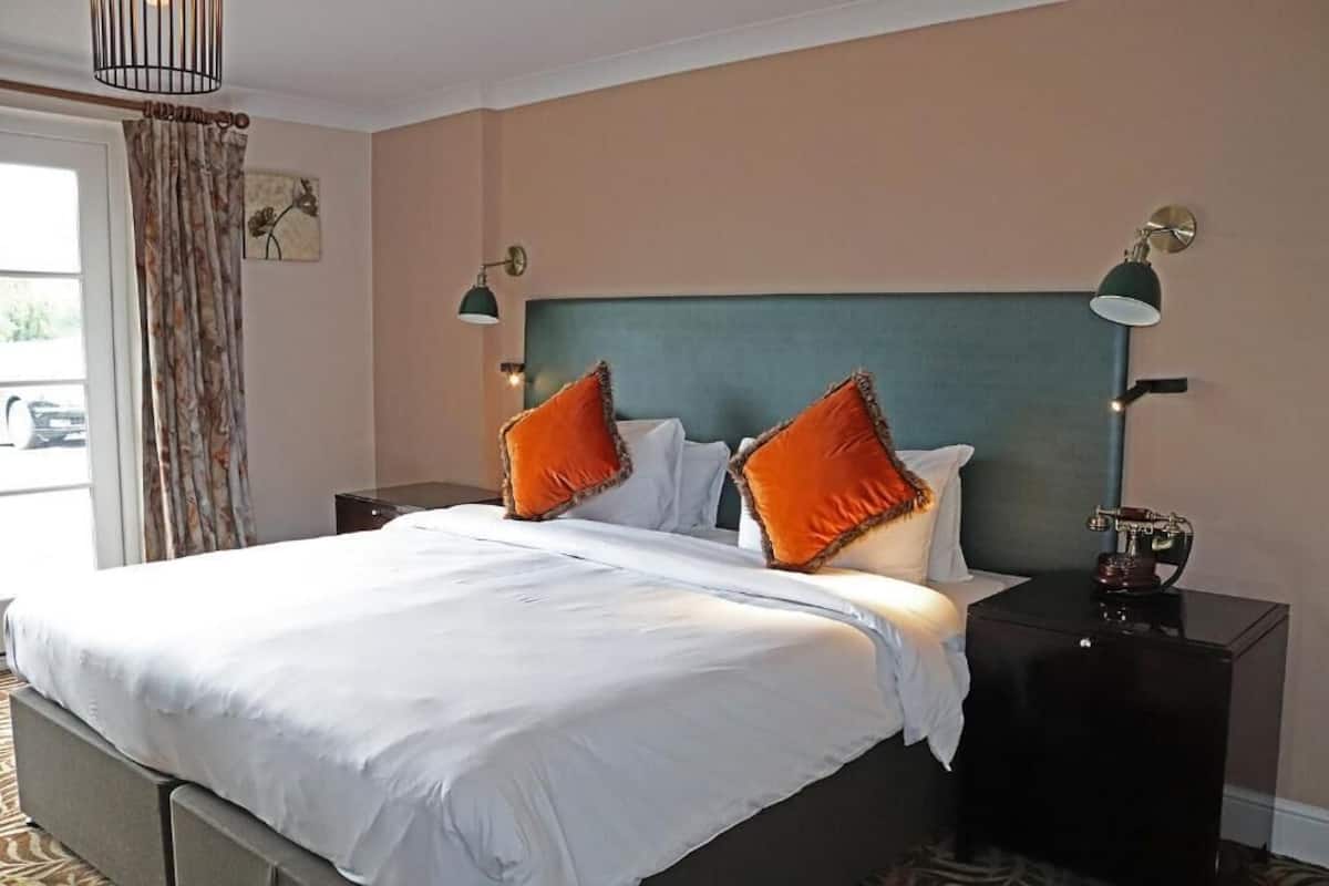 A hotel room with a large bed, two nightstands, and a view of the outdoors.