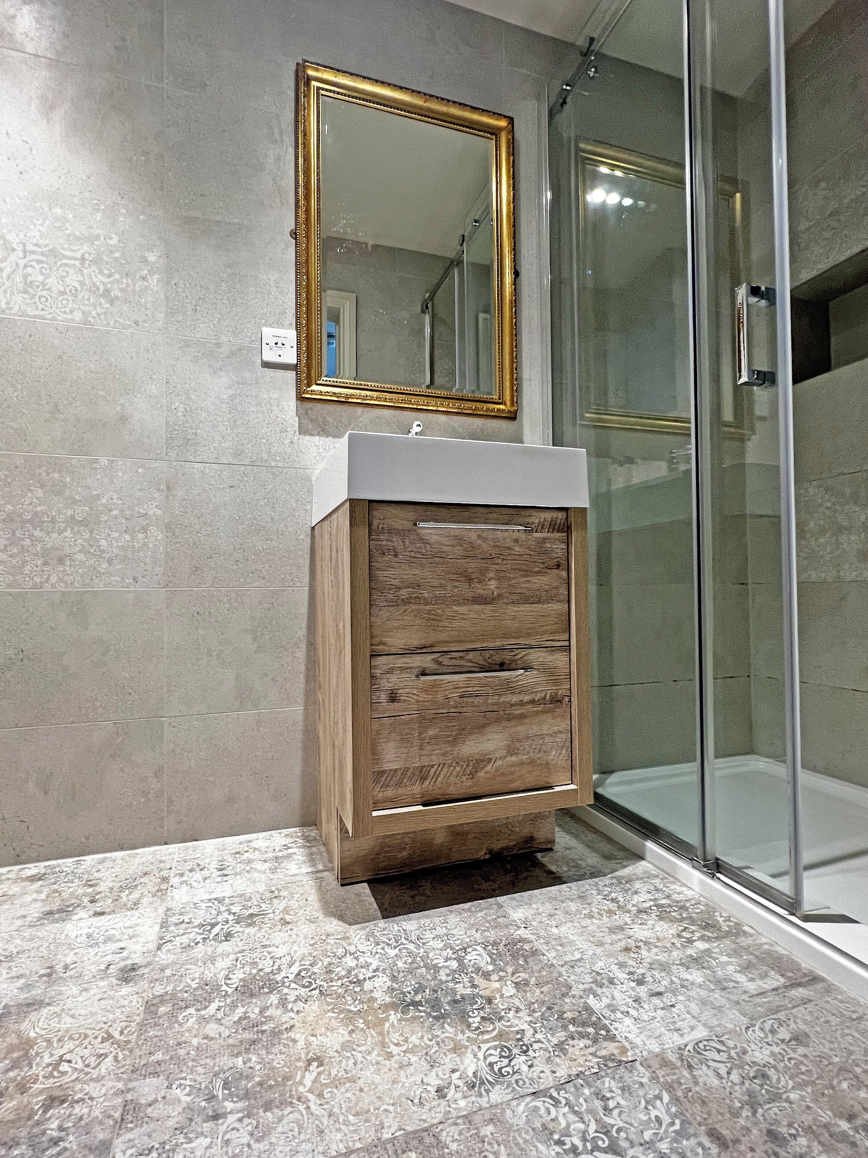 A bathroom with a wooden vanity, a mirror, and a glass shower enclosure.