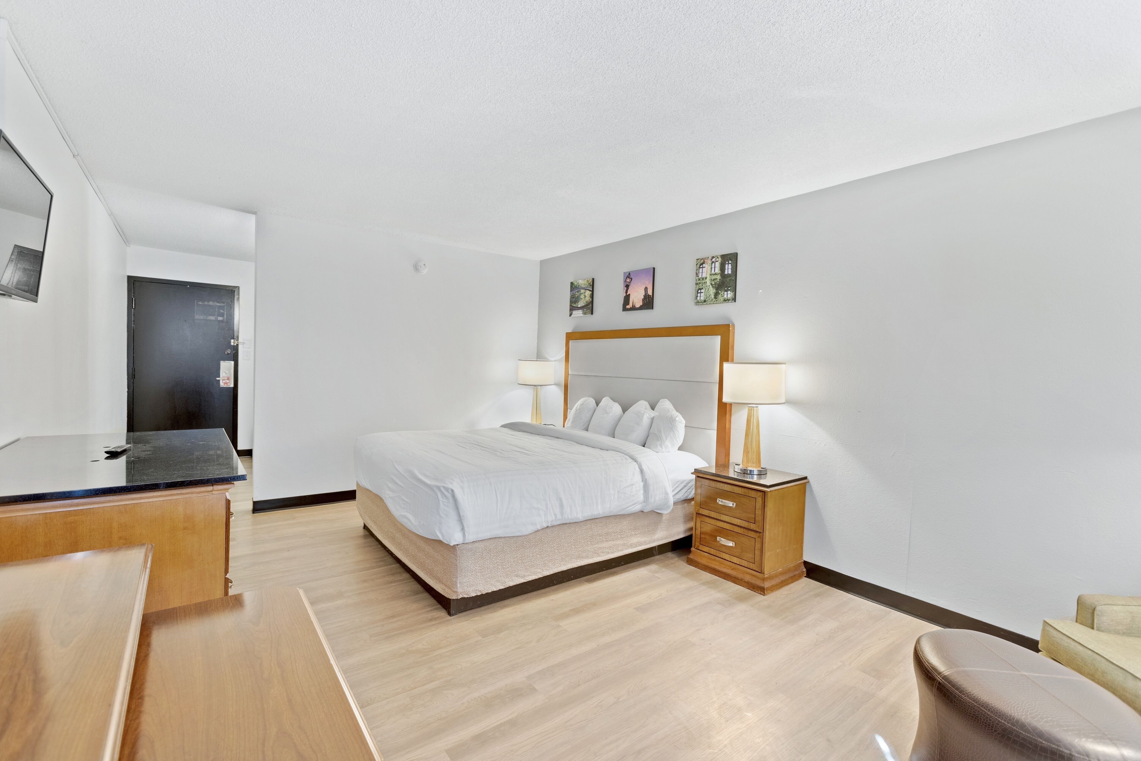 A modern hotel room with a bed, bedside tables, a desk, and a chair.