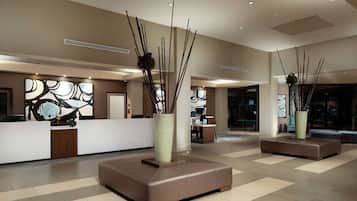A modern lobby with a reception desk, seating areas, and abstract wall art.