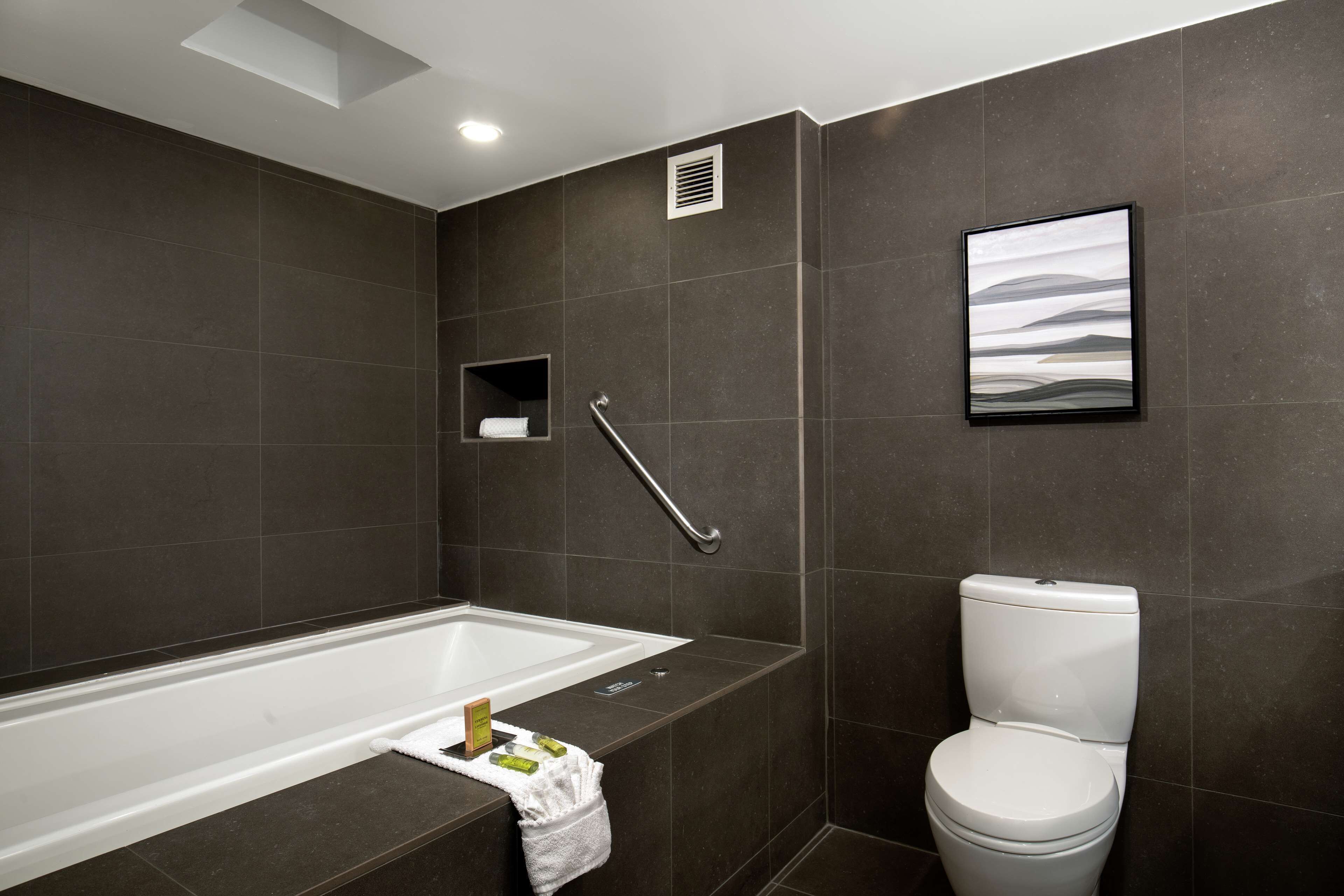 A modern bathroom with a bathtub, toilet, and a towel rack.