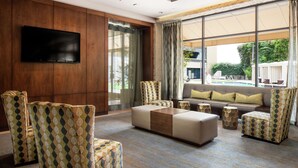 Una sala de estar moderna con un televisor de pantalla plana montado en una pared de madera, sillones con estampado, un sofá modular y una mesa de centro.