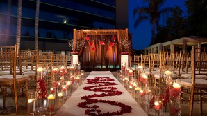 Montaje para una ceremonia de boda en interiores, con un pasillo floral, sillas y un escenario.
