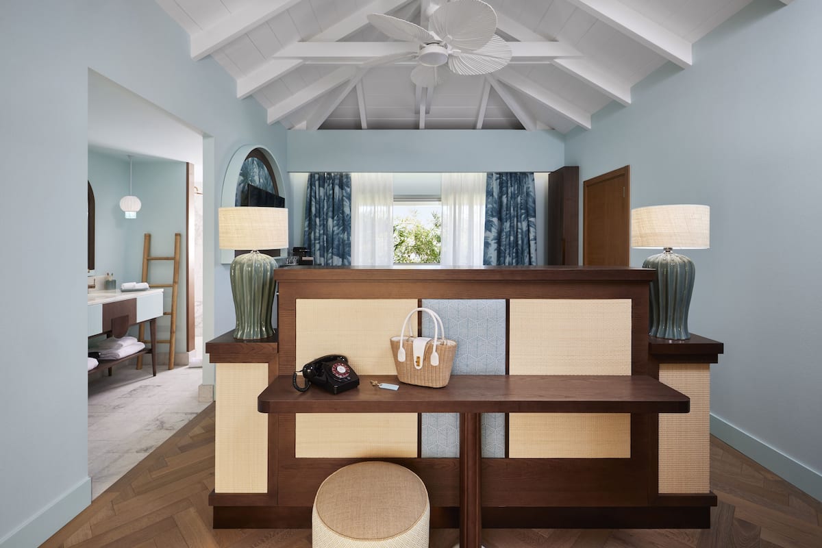 A room with a wooden bench, a telephone, a basket, and a lamp.