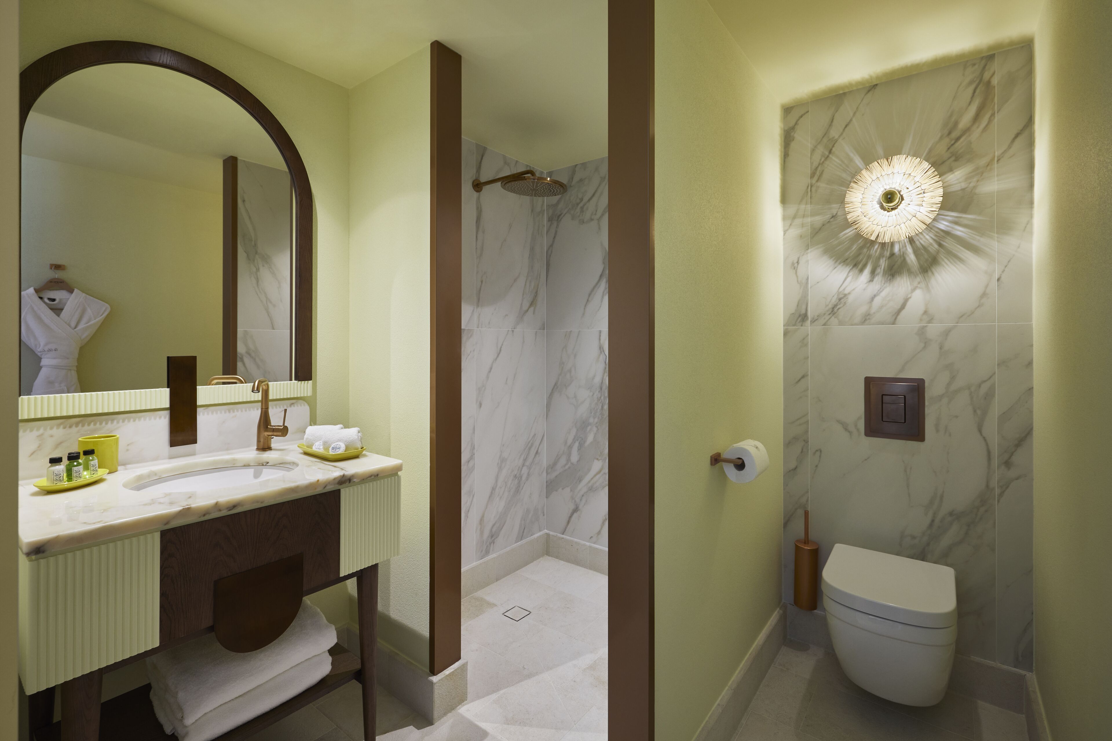 A bathroom with a marble sink, a large mirror, a shower, and a toilet.