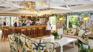 Una zona de bar con mostrador, taburetes y un área de estar con sofá y sillones.