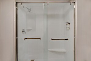 A glass-enclosed shower with a handheld showerhead, a towel rack, and a small shelf. - Holiday Inn Express Rochester - University Area by IHG (Rochester)