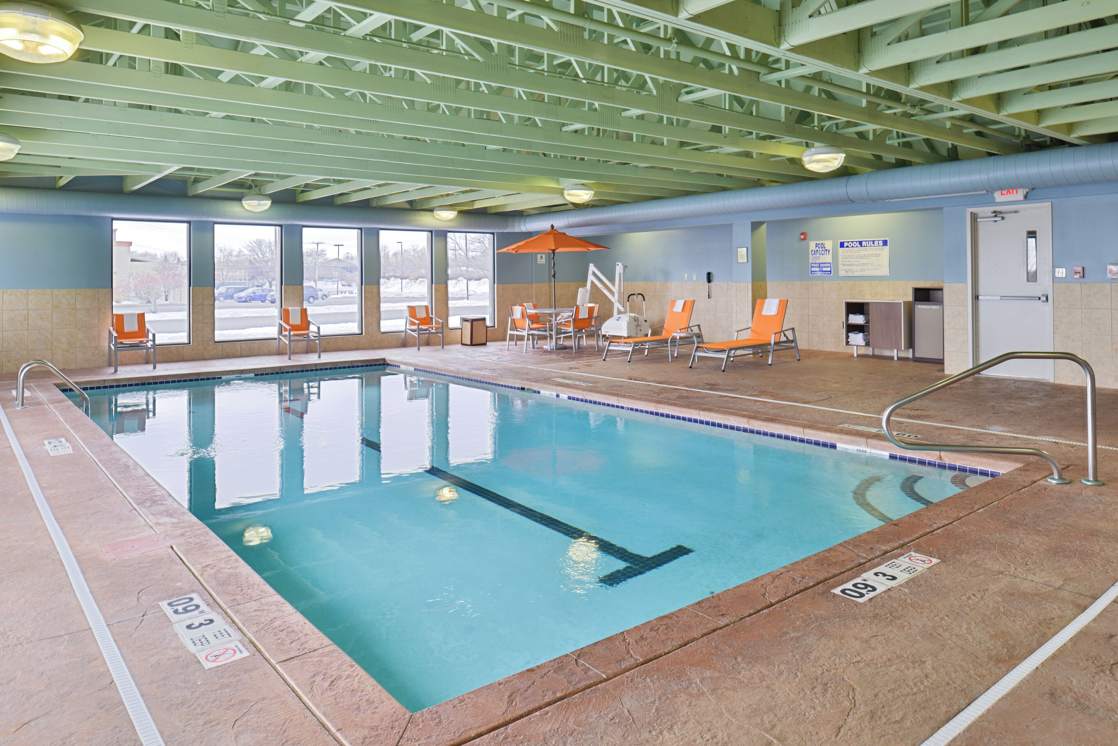 An indoor swimming pool with clear water, surrounded by lounge chairs and a covered seating area.