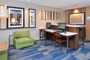 A hotel room with a desk, two monitors, a green armchair, and framed artwork on the wall. - Holiday Inn Express Rochester - University Area by IHG (Rochester)