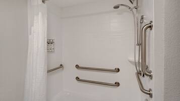 A white bathroom with a shower, grab bars, and a toilet.