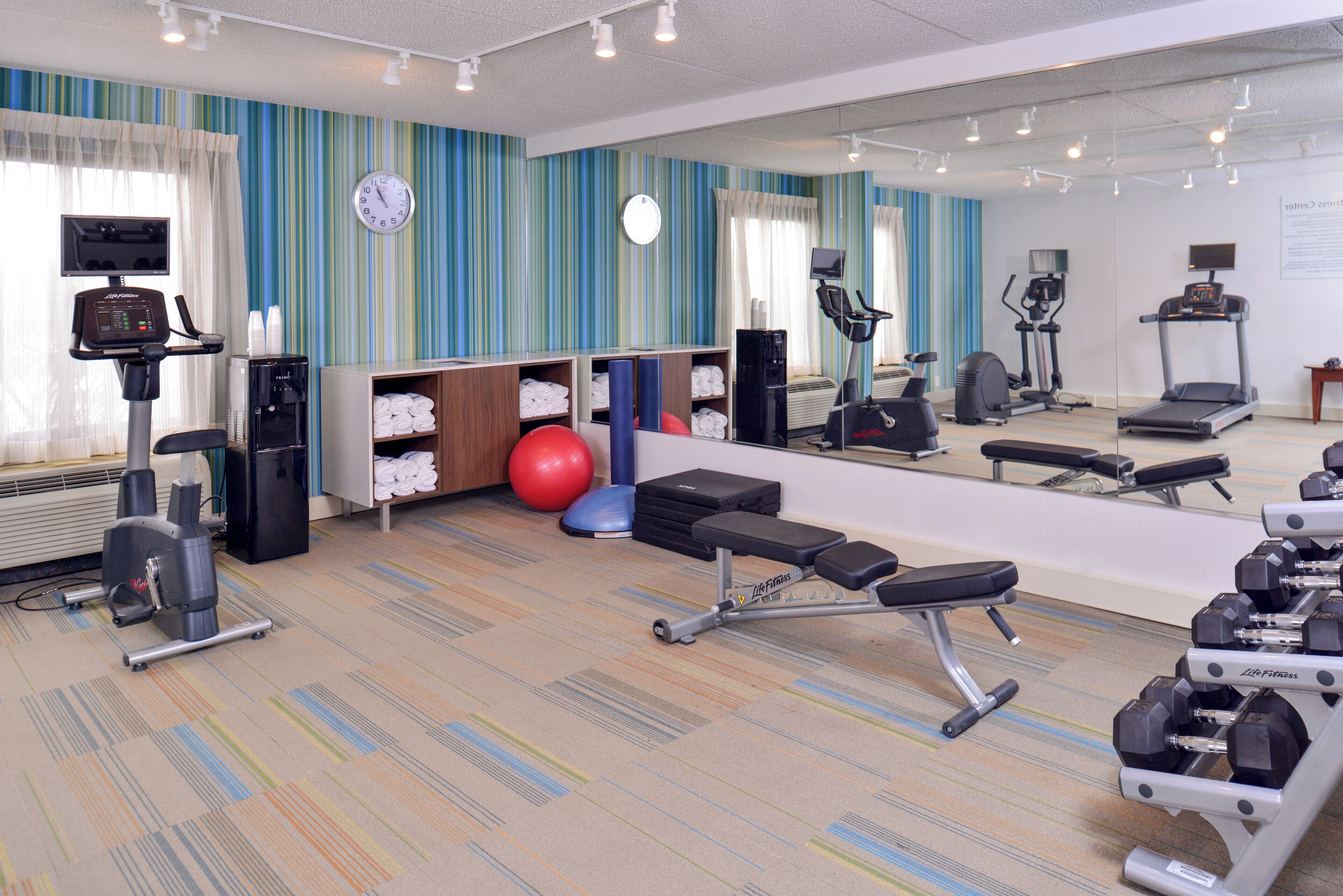 A gym with exercise equipment, a mirror, and a water dispenser.