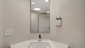 A bathroom with a white sink, a mirror, and a shower door.