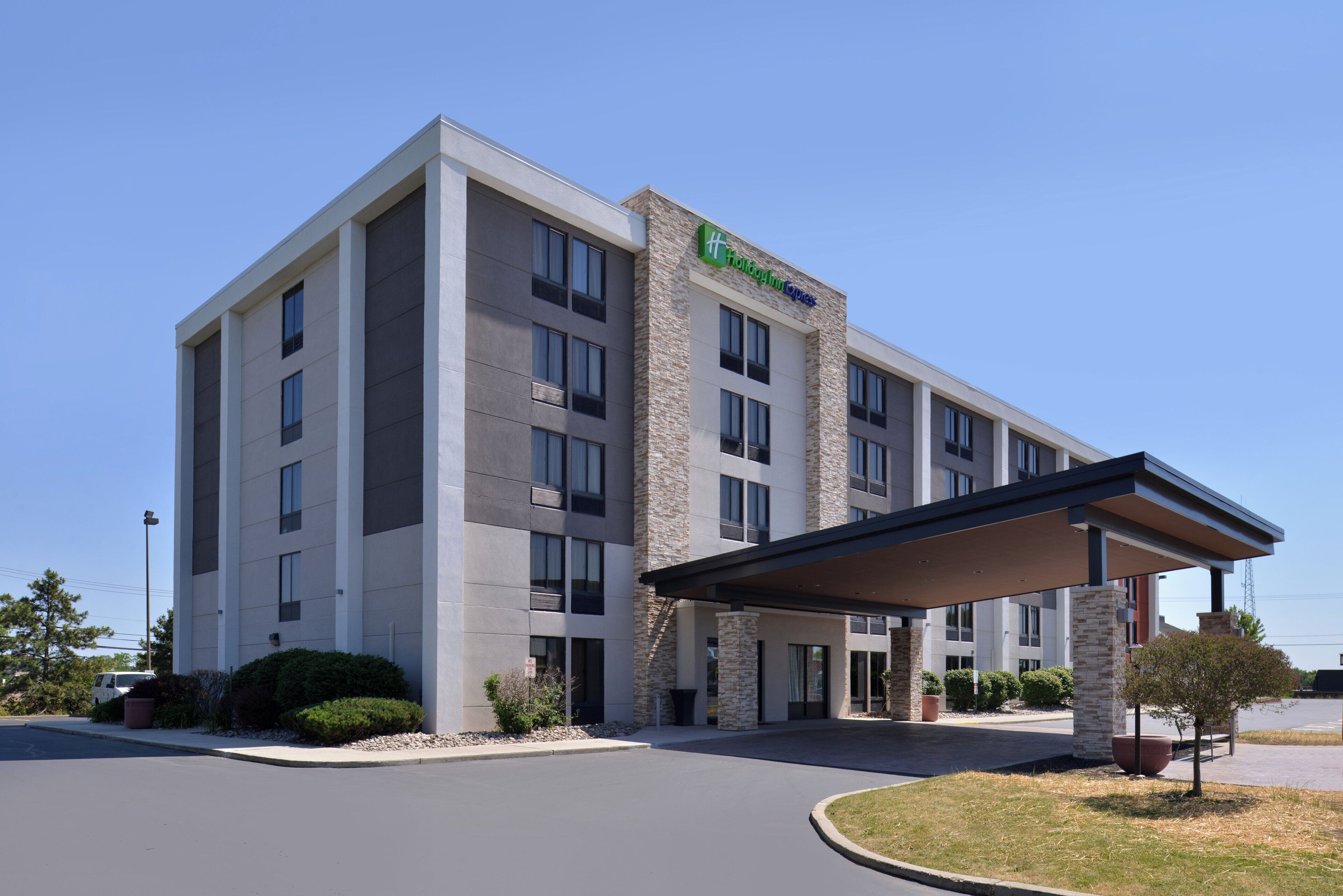 Un hôtel Holiday Inn Express au design moderne, doté d’une entrée abritée et d’un espace de stationnement.