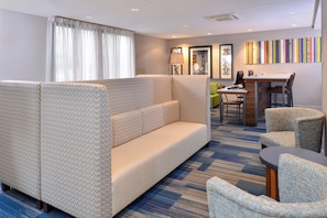 A hotel room with a sectional sofa, a small dining table, and a desk with a computer. - Holiday Inn Express Rochester - University Area by IHG (Rochester)